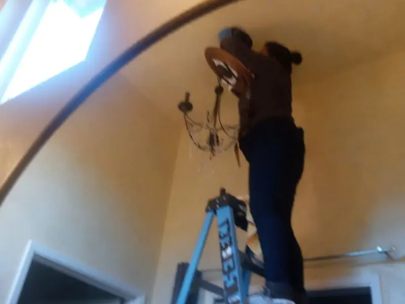 Electrician installing a chandelier in a Abilene residence